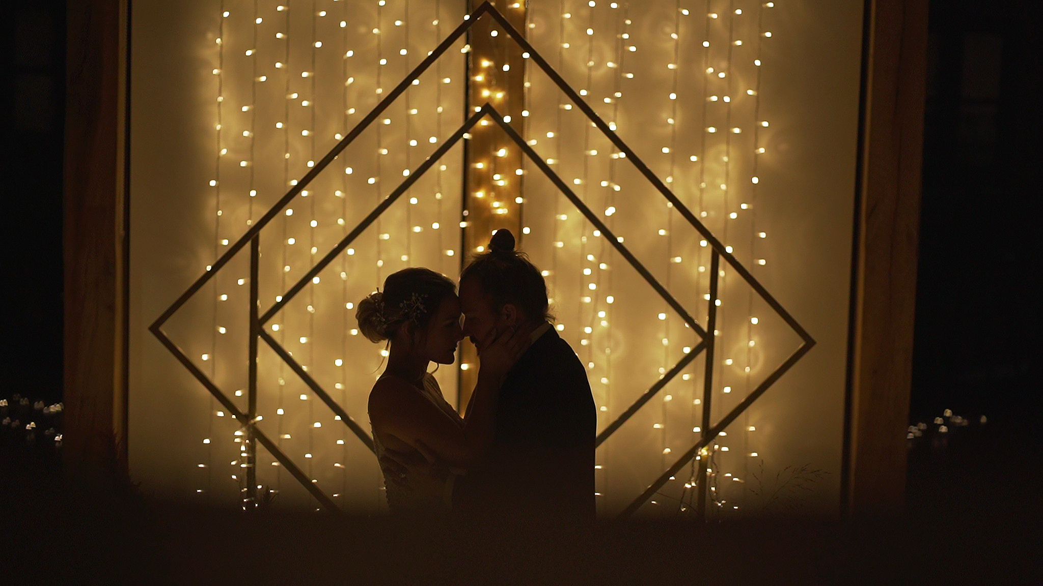 A silhouette of a bride and groom in front of thousands of fairy lights