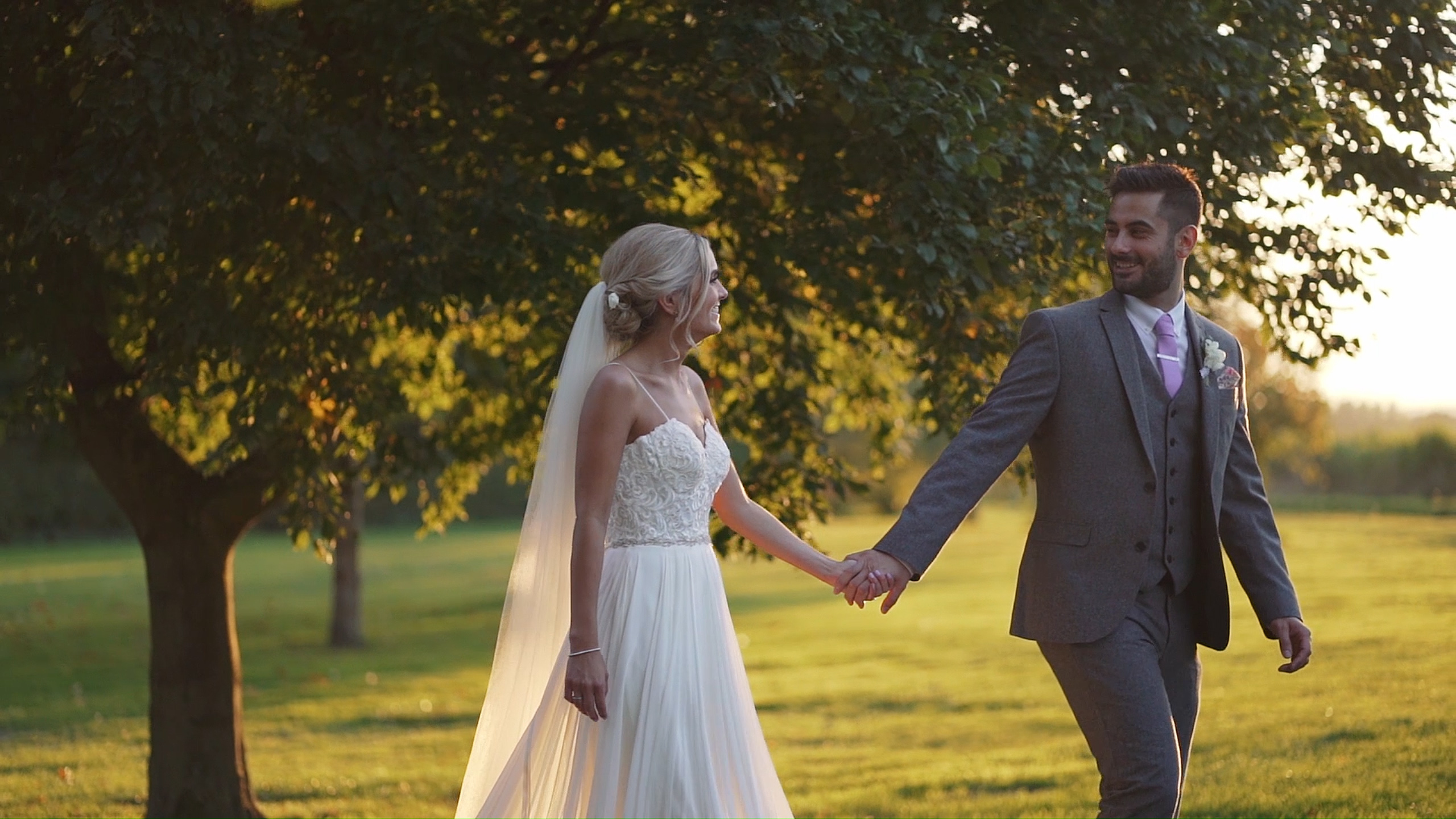 Dan and Sarah, bride and groom walking through fields during golden hour