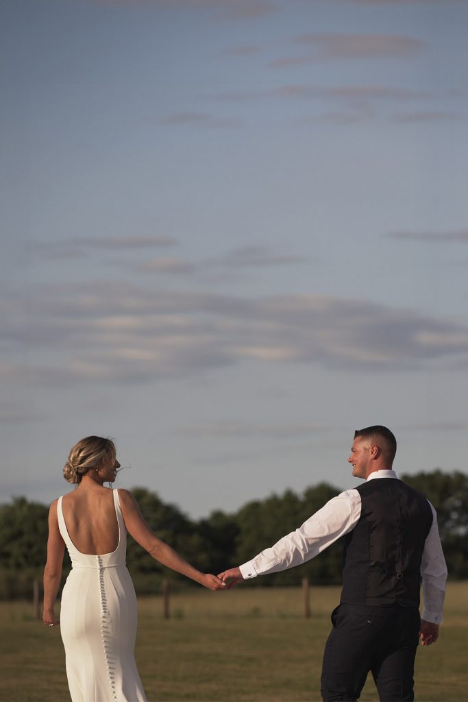 Bride and Groom holding hands while walking together during the evening