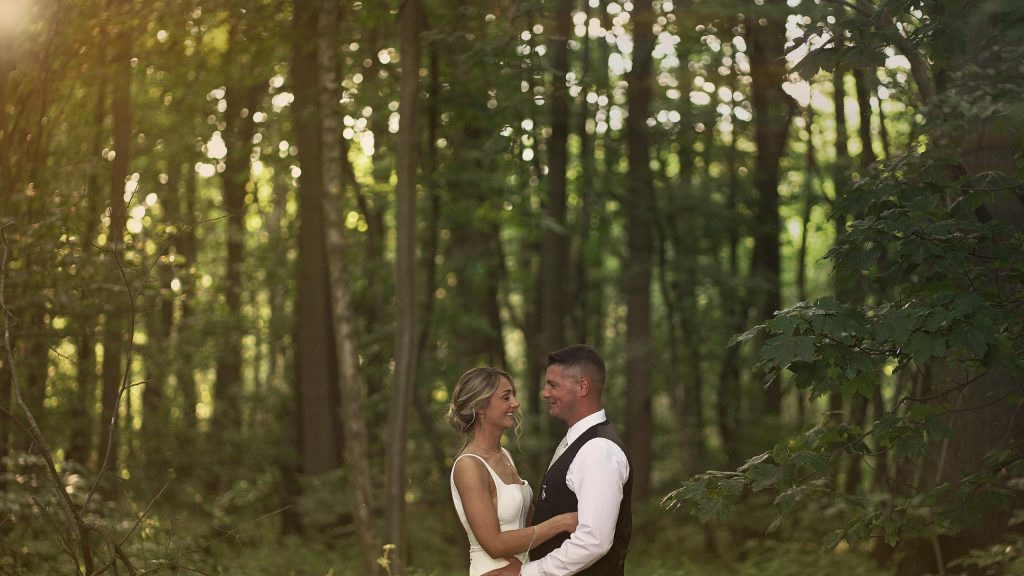 Bride and Groom embrace in front of the forest during sunset