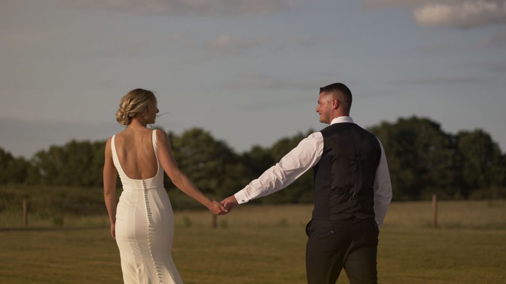 Bride leads groom as they walk around the grounds of Hazel Gap Barn