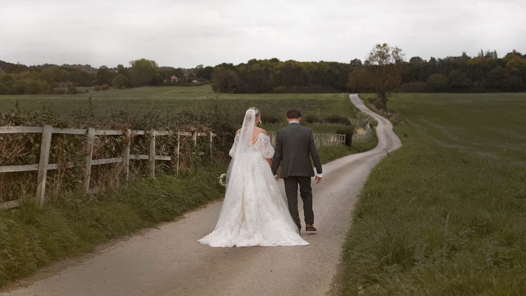Bride and Groom walking down farm track away from venue together