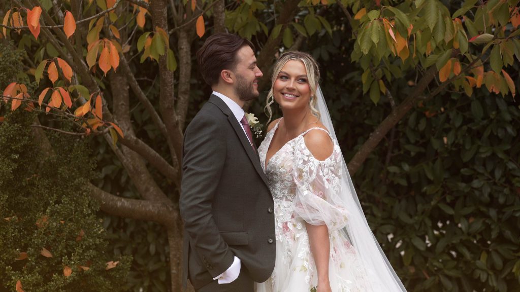 Bride and Groom posing in front of tree with autumn leaves