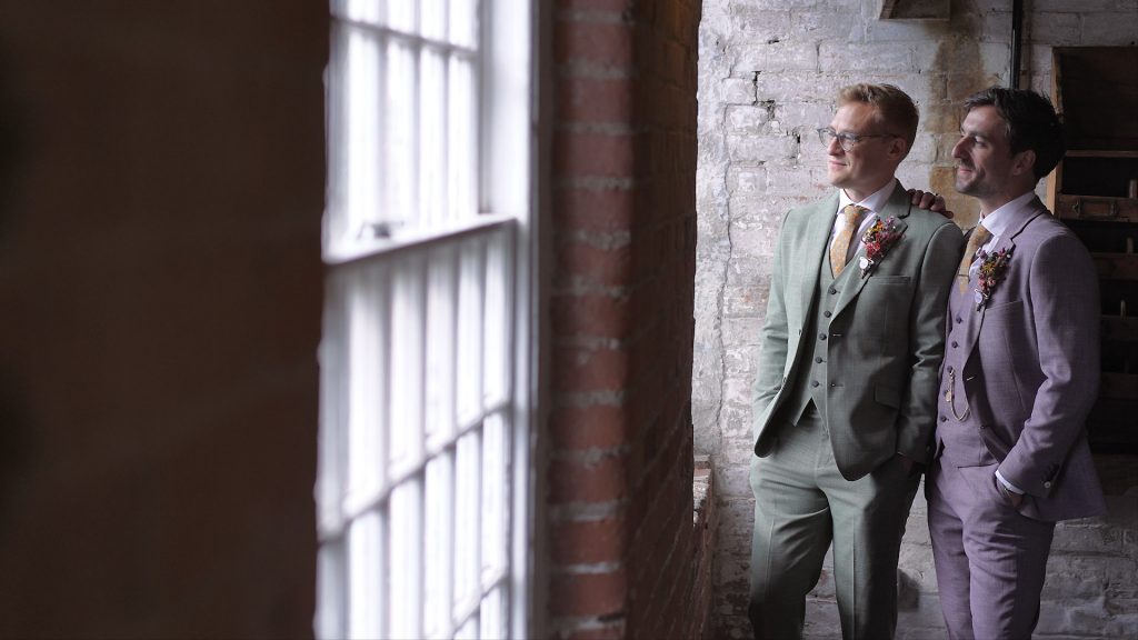 Grooms posing together by the window in the West Mill venue