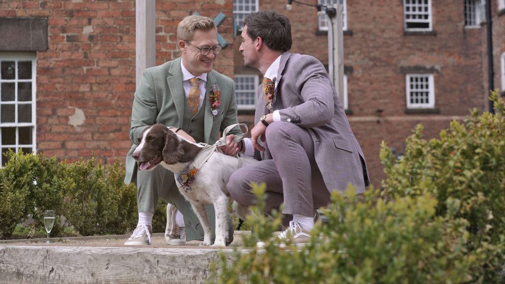 Grooms with their spaniel dog smiling during wedding day