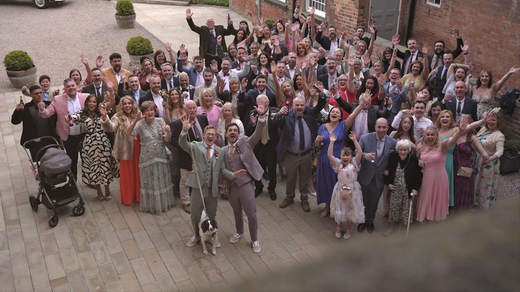 The whole wedding party having a big group cheer at the West Mill venue
