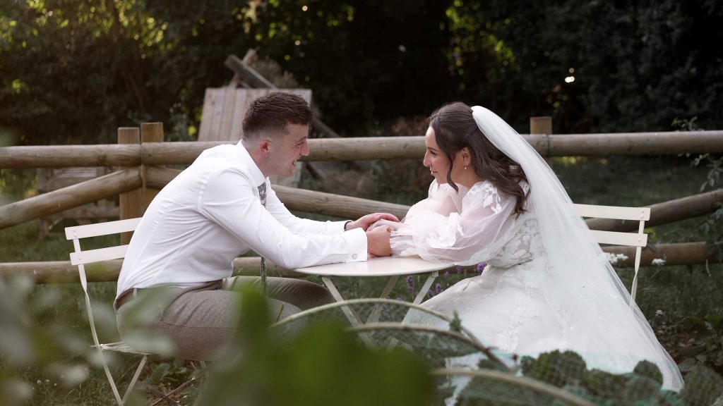 Bride and groom sat at table in gardens during golden hour